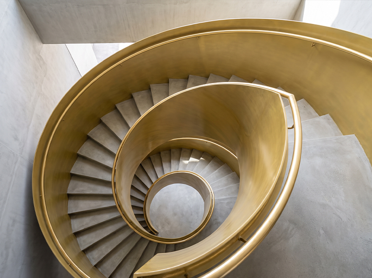 Escalier colimaçon sur mesure en finition laiton avec marches en travertin