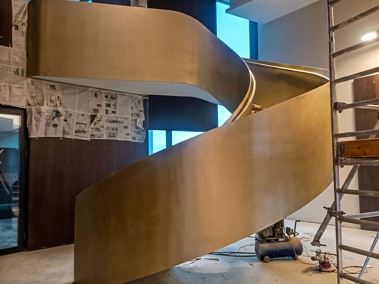 Escalier métallique courbe avec finition dorée en cours de finition intérieure